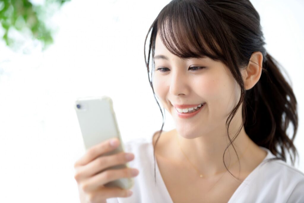 スマホ片手に買取の申込をする女性の写真